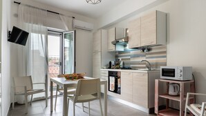 Cozinha moderna com área de refeições, TV na parede e varanda com vista.