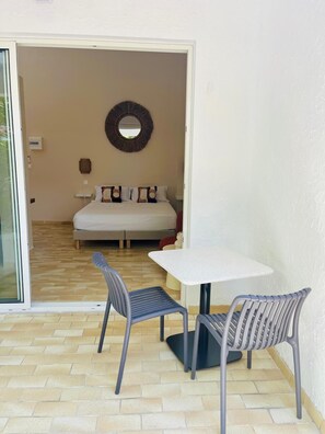 Una habitación con una cama, un espejo redondo en la pared, una mesita y dos sillas.