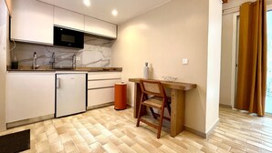 A compact kitchen with a microwave, sink, and small refrigerator. There's a wooden table with a chair and a waste bin. - Studio Colibri - Terrace 2 pers, 3mn from Anse Mitan beach (Les Trois-Îlets)