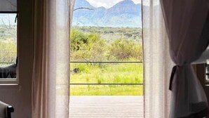 Une pièce dotée d’une grande porte coulissante donnant sur un balcon avec vue sur les montagnes.