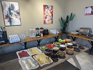 A buffet setup with various food items, coffee machines, and a toaster.