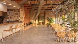 A restaurant with a long counter, wicker chairs, and a tiled floor.
