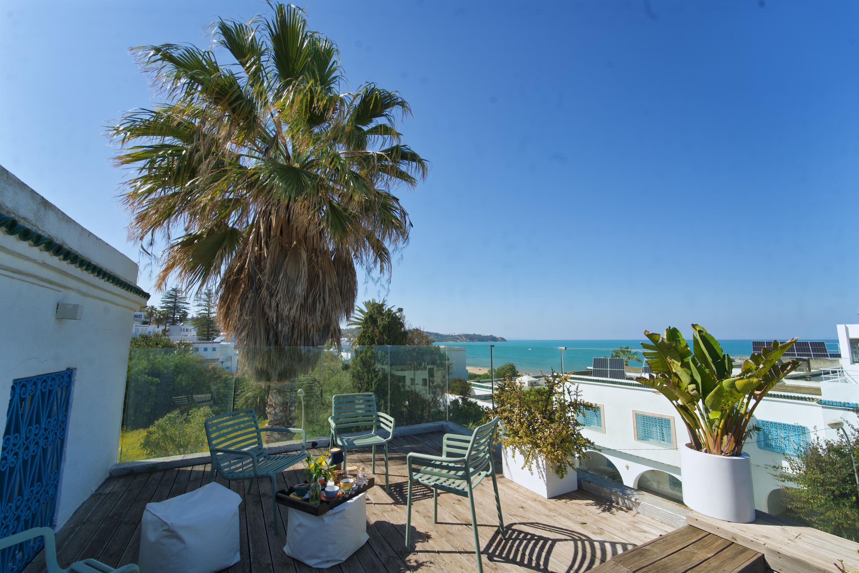 A balcony with chairs, a table, and a potted plant.