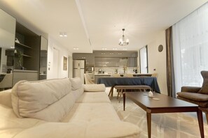 Ein modernes Wohnzimmer mit einer Couch, einem Esstisch und Blick zur Küche.