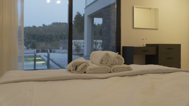 A hotel room with a bed, a bathroom with a mirror, and a view of a building and trees. - Bodrum Yalıçiftlik 4 Ensuite Rooms & Private Pool (Bodrum)