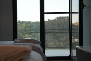 Ein Schlafzimmer mit großem Fenster, einem Bett und einem Schreibtisch.