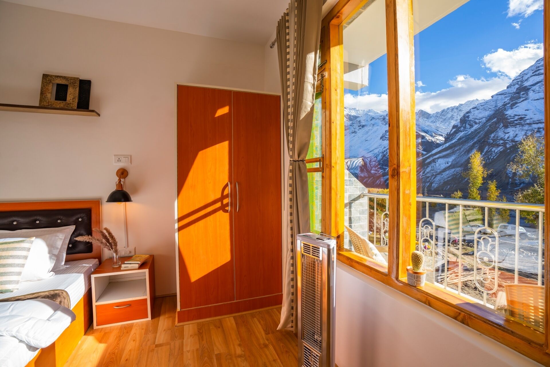 Un dormitorio con cama, armario, calentador y ventana con vista a la montaña.