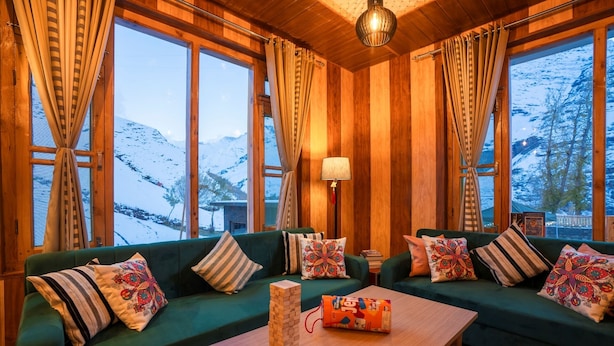 Ein gemütliches Zimmer mit Holzwänden, einem grünen Sofagarnitur, einem Holztisch und einer Lampe.