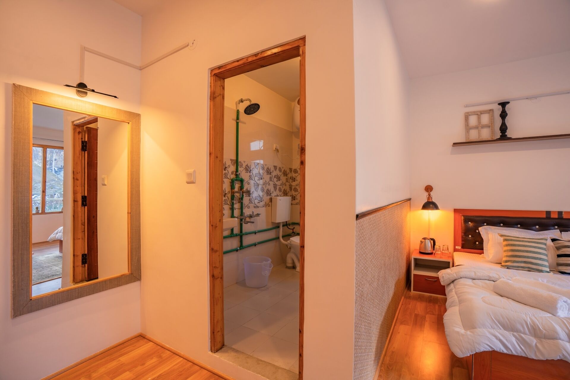 Un dormitorio con cama de madera, una mesita de noche, un tocador, un espejo y vistas al baño.