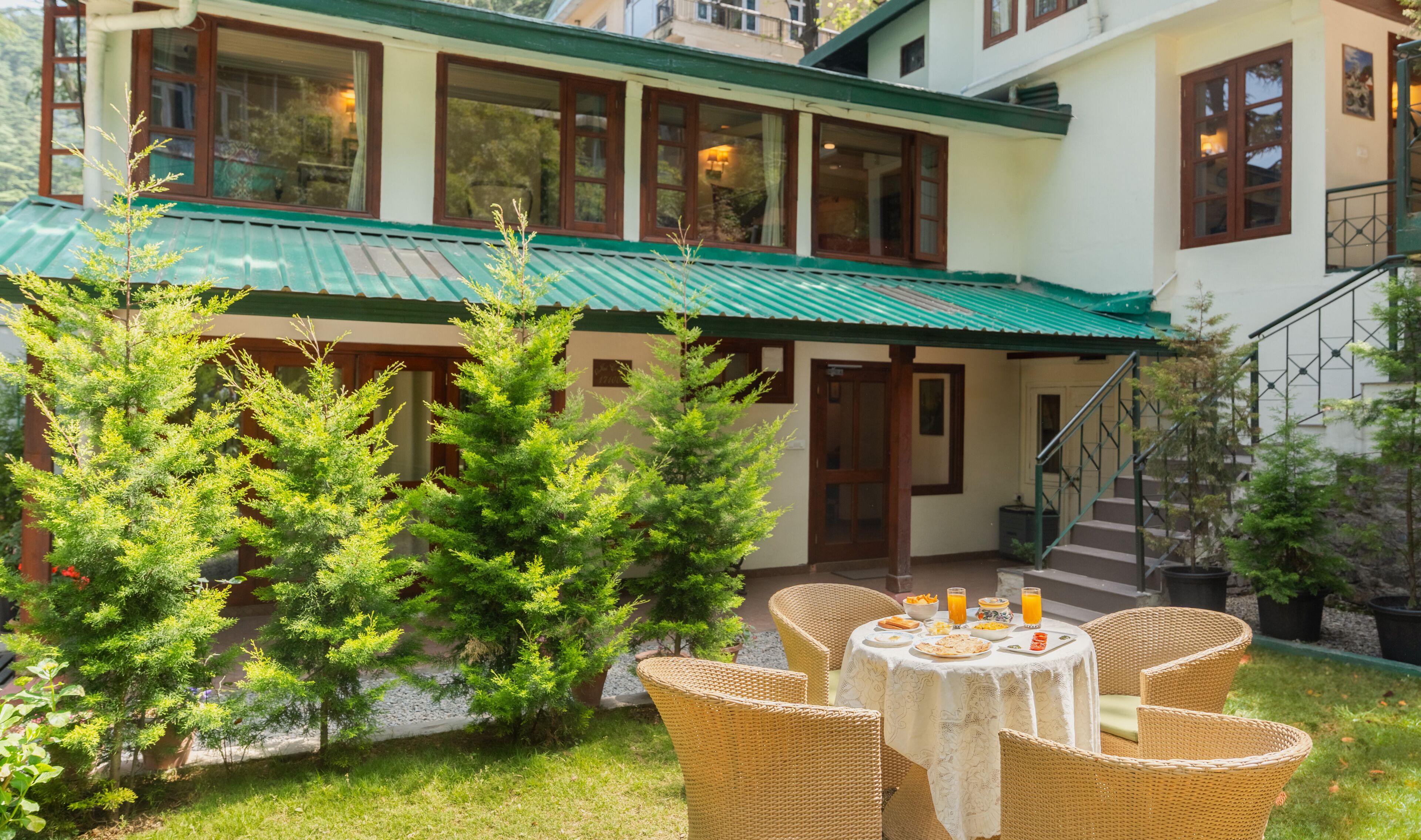 A building with a green roof, a staircase, and a table with breakfast items.