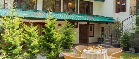 A building with a green roof, a staircase, and a table with breakfast items.