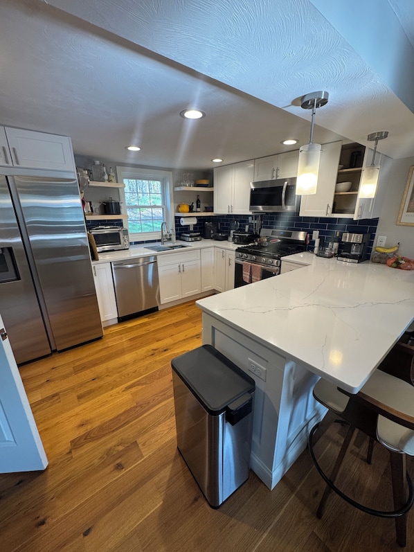 A modern kitchen with stainless steel appliances, a large island, and wooden flooring.