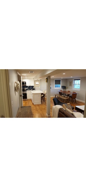 A modern kitchen with white cabinets, a dining area with a wooden table and chairs, and a cozy seating area with a sofa.