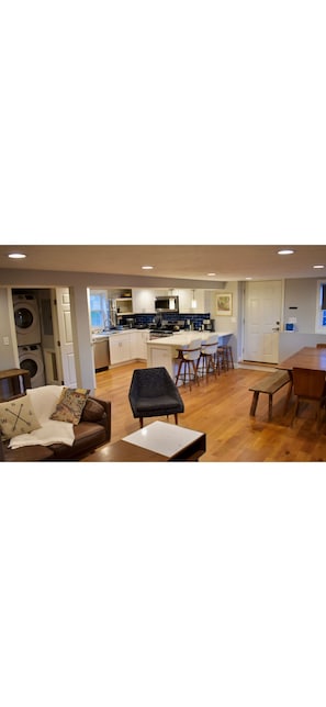 A modern living room with a sofa, a coffee table, and a dining area with a bench and chairs.