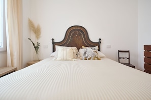 A bed with a wooden headboard, white bedding, and decorative pillows. - BRIGHT LUXURY APARTMENT (Milano)