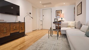 A living room with a flat-screen TV, a wooden cabinet, a sofa, a lamp, and a door. - BRIGHT LUXURY APARTMENT (Milano)