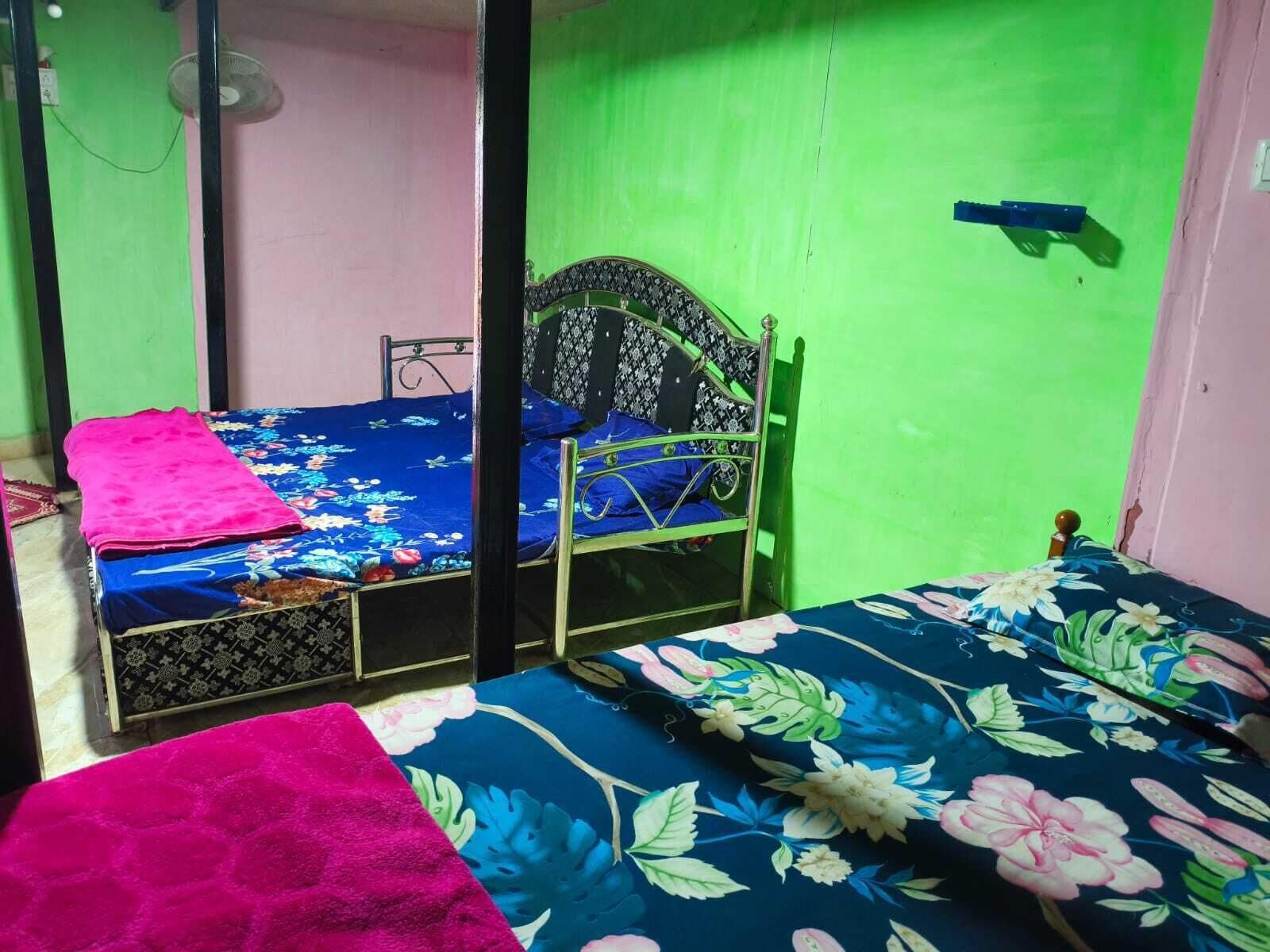 A room with two beds, one with a floral bedspread and the other with a patterned bedspread.
