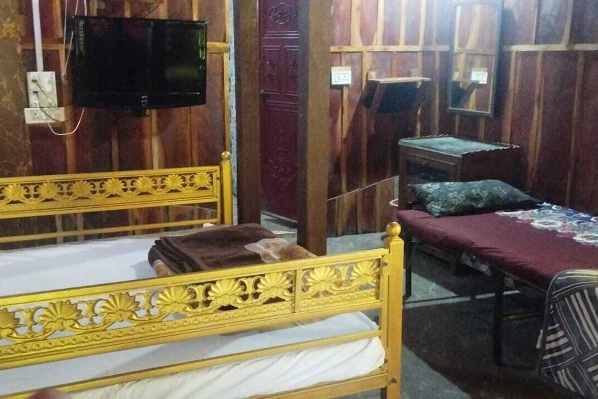 Una habitación con dos camas, un televisor, una mesita y un espejo.