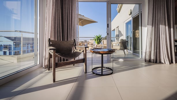 A modern room with a large window, a chair, a small round table, and a view of the outside.
