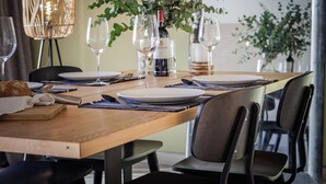 A dining table set with plates, glasses, and cutlery, with a bottle of wine and a candle in the background.