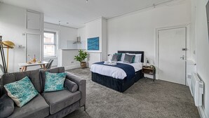 Ein Schlafzimmer mit Bett, Sofa, Schreibtisch und einer Topfpflanze.