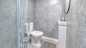 Ein Badezimmer mit Duschkabine, Toilette, Waschbecken und Spiegel.