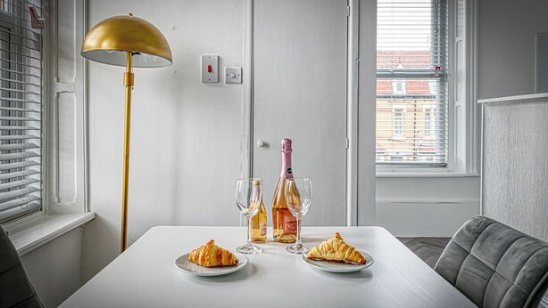 Ein Esstisch mit zwei Tellern Croissants, zwei Weingläsern und einer Weinflasche.