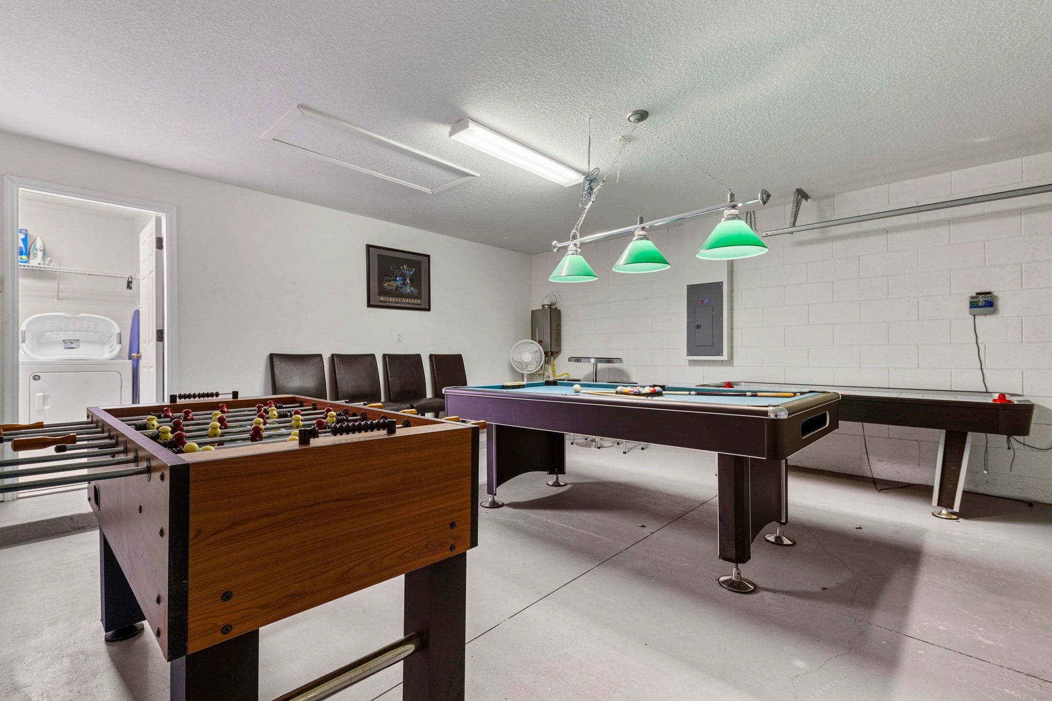 Une pièce équipée d’un baby-foot, d’une table de billard et d’un ventilateur.