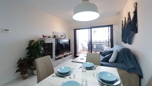 En moderne stue med spiseplads, TV og balkon med udsigt.