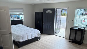 A bedroom with a bed, a wardrobe, a desk, and a door leading to an outdoor area. - Private studio in north Long Beach with refreshing AC (Long Beach)