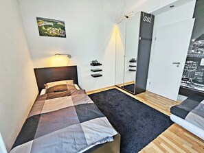 A bedroom with a bed, a mirror, a wardrobe, and a cityscape wall art. - Vacation home / apartment in Koblenz with terrace (Koblenz)