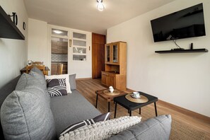 Una sala de estar moderna con un sofá, una mesita de centro y un televisor de pantalla plana montado en la pared.
