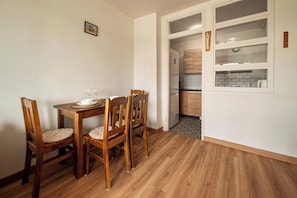 A dining area with a wooden table and chairs, a kitchen visible through an open door, and a framed picture on the wall. - RentPlanet - Apartament przy Parku Tołpy (Wrocław)
