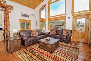 A spacious living room with a large sectional sofa, a wooden coffee table, and a striped rug. - New! Hollow Pine Lodge | Hot Tub + Updated Mountain Retreat Near RMNP (Grand Lake)