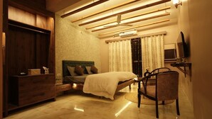 A bedroom with a bed, a dresser, a chair, a television, and a ceiling fan. - Stay Stories (Chopra)