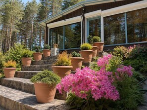 A house with a glass conservatory, stone steps, and potted plants.