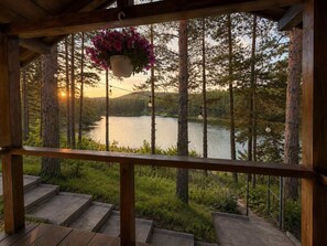 A wooden deck with a hanging flower pot, a view of a lake surrounded by trees, and a clear sky. - Club Paradise Bay Iskar Lake (Sofia)