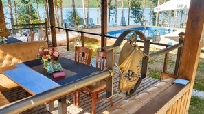 A wooden deck with a table and chairs, a bench, and a view of a swimming pool. - Club Paradise Bay Iskar Lake (Sofia)