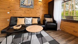 A wooden interior with a sofa, a chair, a round table, and a painting of a sailboat. - Club Paradise Bay Iskar Lake (Sofia)