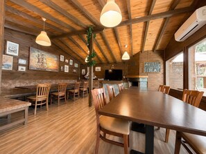 Un interior de madera con una larga mesa de comedor, sillas y un televisor.