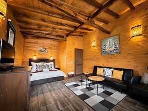Una habitación tipo cabaña de madera con una cama, un sofá, una mesita y un cuadro en la pared.
