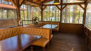 A wooden deck with a bench and table, large windows, and a view of trees. - Club Paradise Bay Iskar Lake (Sofia)