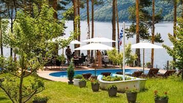 A poolside area with outdoor seating, a flag, and a view of the lake.