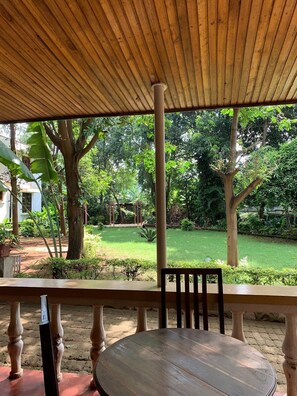 Ein überdachter Außenbereich mit Blick auf einen Garten und Bäume.