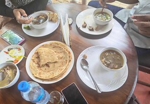 A dining table with various dishes, including soup and flatbreads, and a water bottle.
