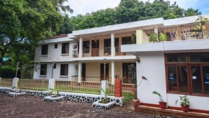 A two-story building with a balcony, a covered porch, and a garden area with potted plants. - kilimanjaro safari lodge (Moshi)