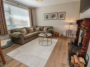 A living room with a sofa, a coffee table, a fireplace, and framed pictures on the wall. - Castaway Cottage Maidens (Girvan)