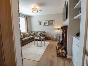 A living room with a sofa, a coffee table, a fireplace, and a TV mounted on the wall.