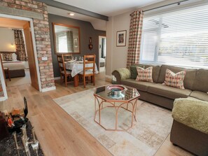 A living room with a dining area, a sofa, a coffee table, and a fireplace. - Castaway Cottage Maidens (Girvan)