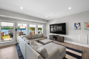 A modern living room with a sectional sofa, a flat-screen TV, and large windows overlooking a pool. - Kiser Island (Terrell)